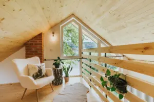 Poddasze w domku Jeleni Szlak z fotelem przy oknie i drewnianą balustradą